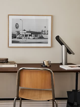 Hjemmekontor med træstol, skrivebordslampe og indrammet sort-hvid foto på væggen