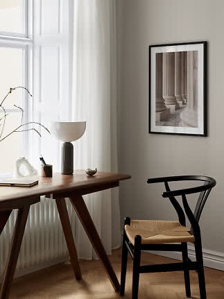 Framed art print of classical columns above a desk in a bright, modern room