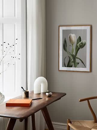 Framed tulip print above a wooden desk in a bright, minimalist room.