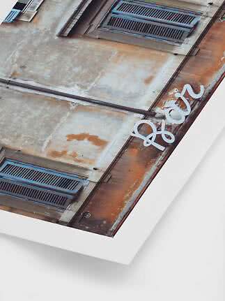 Angled photo of a weathered building facade with blue shutters and white "hey" lettering