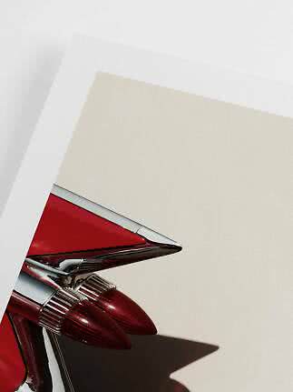 Close-up of red classic car tail fin with chrome details against a light wall