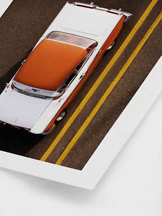 Schräg von oben fotografiertes orange-weißes klassisches Cabrio auf einer Straße mit gelben Linien