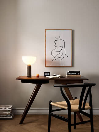 Bureau en bois foncé avec chaise, lampe allumée, livres et dessin encadré au mur