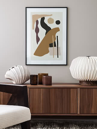 Framed abstract print with organic shapes above a wooden sideboard