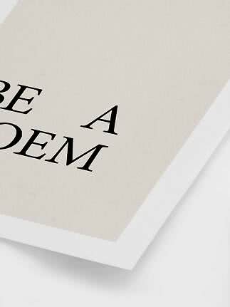Nærbillede af minimalistisk plakat med sort typografi på cremefarvet papir i hvid ramme