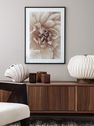Framed beige floral print above a wooden sideboard with a sculptural lamp and small vases