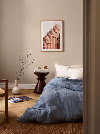 Affiche encadrée de dômes roses au-dessus d’un lit dans une chambre beige