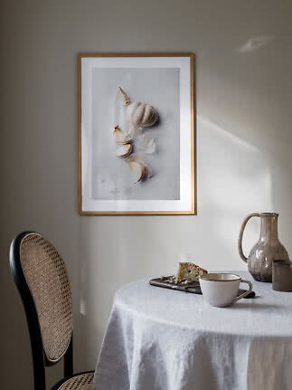 Inramad kökstavla med vitlök på ljus bakgrund ovanför ett dukat bord