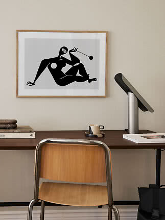 Gerahmter abstrakter Kunstdruck mit schwarzer sitzender Figur über einem Schreibtisch