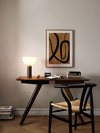 Donkerhouten bureau met stoel, brandende tafellamp en abstracte poster aan de muur