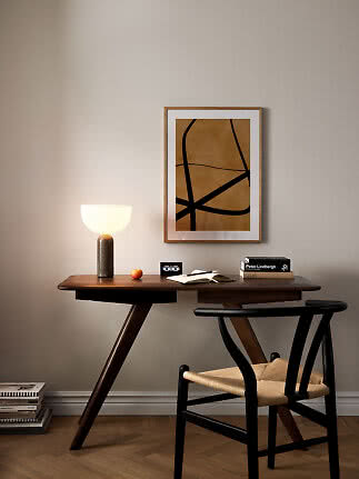 Holzschreibtisch mit leuchtender Tischlampe, Stuhl, Büchern und abstraktem Wandbild