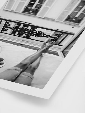 Schwarz-Weiß-Poster mit Person im Bett, Beine hoch zu offenem Fenster und Balkon.