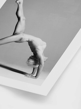 Woman in light activewear balancing on her hands in an artistic black-and-white pose