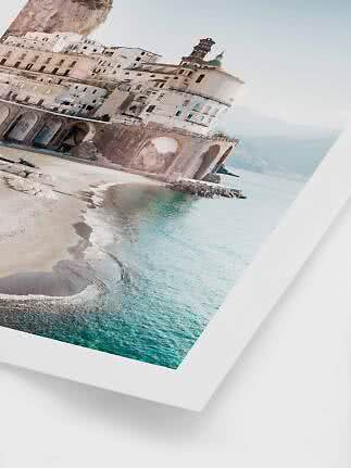 Angled photo of a coastal town with beach, arches and church dome by turquoise sea