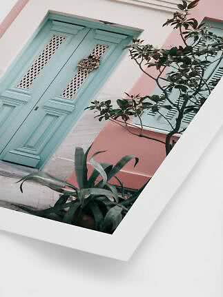 Light blue door on a pink and white facade with plants in the foreground