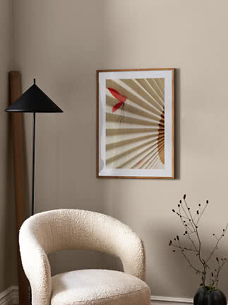 Coin minimaliste avec fauteuil crème, lampadaire noir et œuvre encadrée sur mur beige