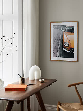 Indrammet foto af orange veteranbil på beige væg over et træskrivebord