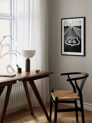 Sort-hvid Route 66 plakat i sort ramme over skrivebord og stol i lyst, moderne rum