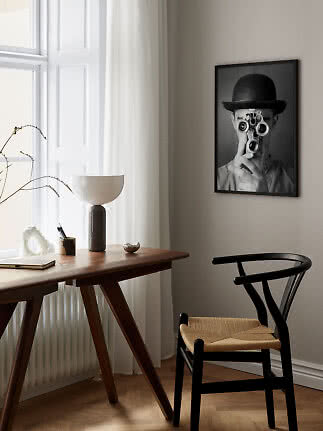 Minimalistisches Homeoffice mit Holztisch, schwarzem Stuhl und Schwarzweißposter an der Wand