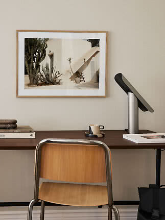 Framed photo print of a white building with outdoor stairs and cactus above a desk