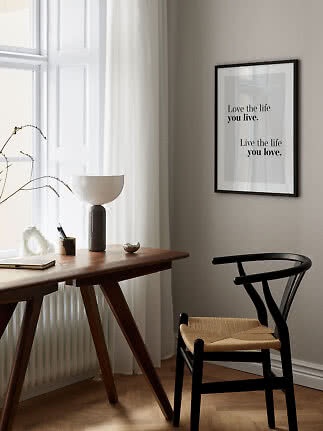 Minimalist home office with wooden desk, black chair, and framed quote print on the wall
