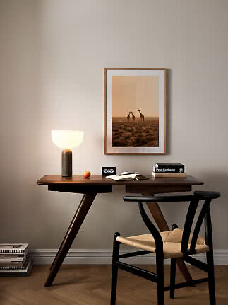 Dunkler Holzschreibtisch mit Stuhl, Lampe und gerahmtem Giraffenbild an der Wand