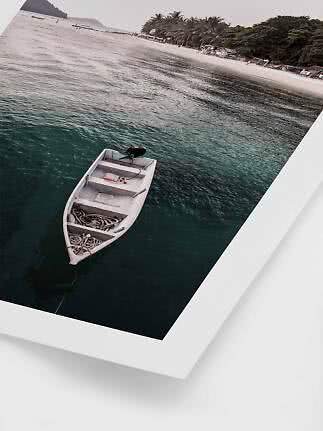 Small white boat moored in clear water near a palm-lined sandy beach