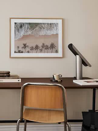 Gerahmter Stranddruck über Schreibtisch mit Stuhl, Lampe, Büchern und Tasse