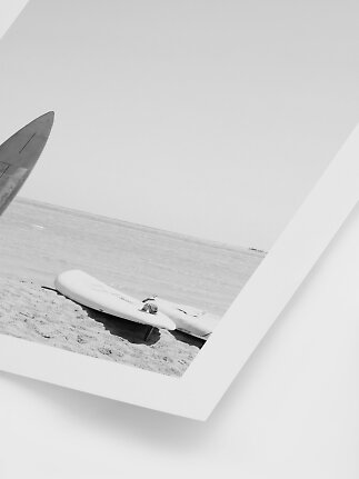 Sort-hvidt strandfoto med surfbrætter i sandet ved havet i hvid ramme