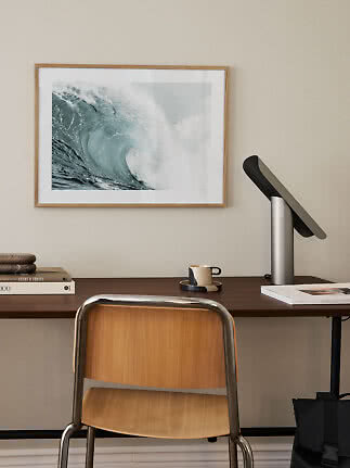 Desk with chair, lamp and framed ocean wave print on the wall