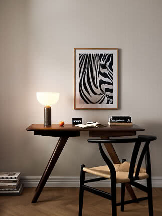 Scrivania in legno scuro con lampada accesa, sedia e stampa di zebra incorniciata