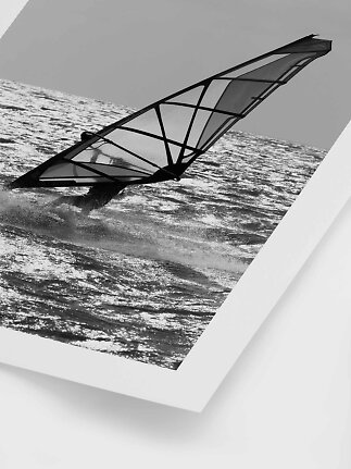Tirage photo noir et blanc d’un véliplanchiste sur l’eau scintillante, avec bord blanc.