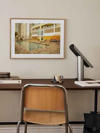 Framed photo of a pool area by a modern apartment building above a desk