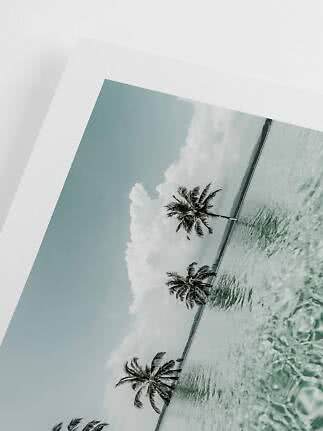 Gerahmtes Foto eines tropischen Strands mit Palmen, ruhigem Meer und Wolken