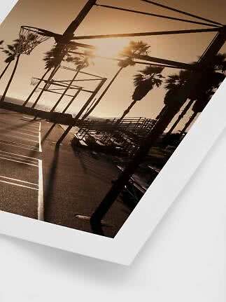 Beachside basketball courts at sunset with palm trees and empty bleachers