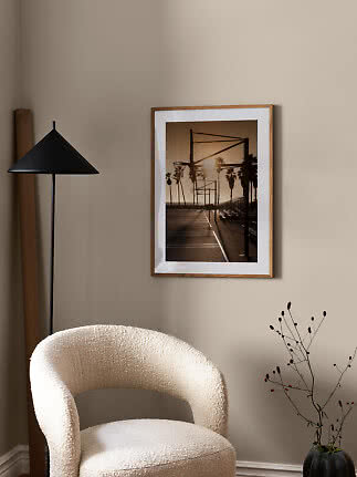 Framed poster of a basketball court with palm trees at sunset on a beige wall