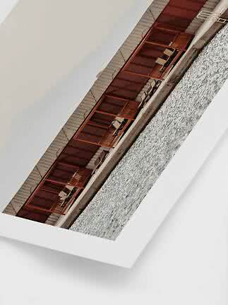 Angled print of wooden waterfront terraces with lounge chairs, bordered in white