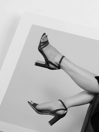 Black strappy block heel sandals worn on raised legs