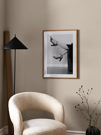 Living room corner with cream armchair, black floor lamp and framed black-and-white print on beige wall