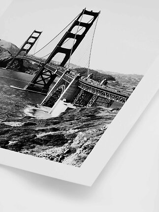 Black-and-white photo of the Golden Gate Bridge from an angled view over water and rocks