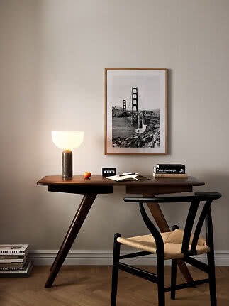 Modern dark wood desk with table lamp, chair, and framed black-and-white bridge print
