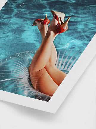 Legs raised in a pool on a clear float, wearing red snakeskin slingback heels