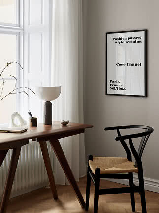 Poster tipografico Coco Chanel incorniciato sopra scrivania in legno vicino a finestra
