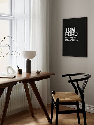 Sort indrammet Tom Ford-typografiplakat over skrivebord og sort stol i lyst, moderne rum