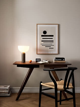 Dark wooden desk with chair, lit table lamp, and abstract wall art