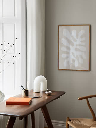 Angolo minimalista con tavolo in legno, poster astratto, lampada bianca, libro e sedia