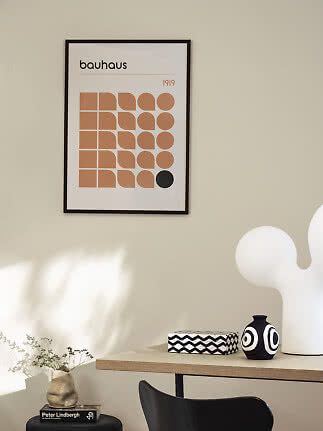 Indrammet Bauhaus-plakat med geometriske former i beige og sort på lys væg