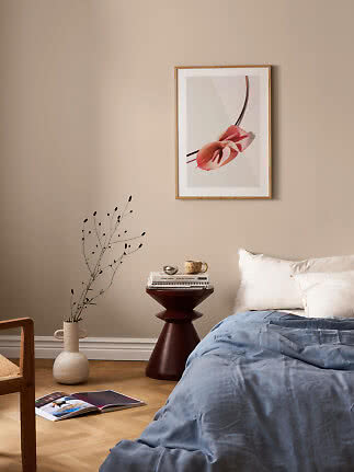 Slaapkamer met blauw dekbed, houten bijzettafel en ingelijste bloemenposter aan beige muur