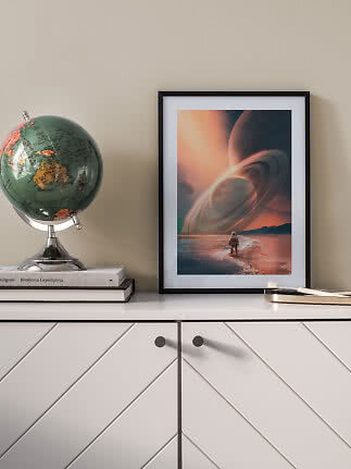 Indrammet sci-fi plakat med ringplanet over strand, placeret på hvid skænk ved siden af en globus