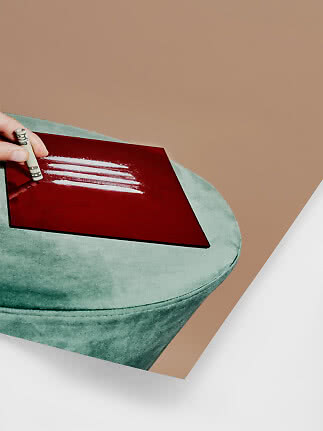 Mano con banconota arrotolata sopra uno specchio rosso con quattro linee bianche su pouf verde